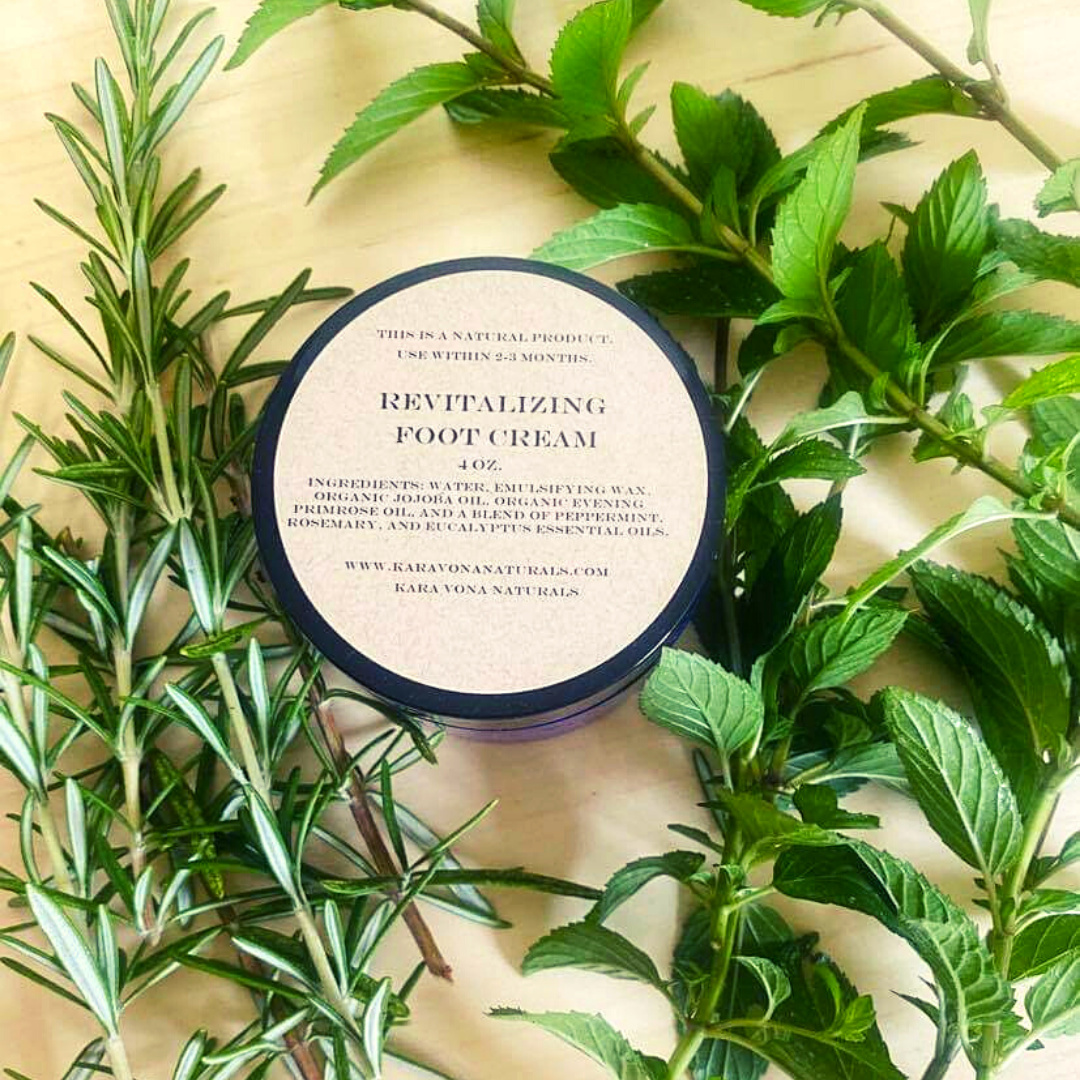 Black jar of revitalizing foot cream on a table surrounded by greenery