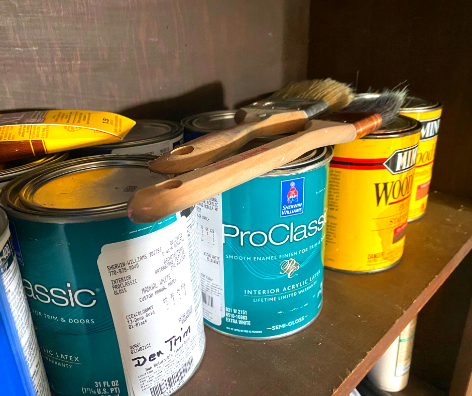 cans of old paint on a brown shelf